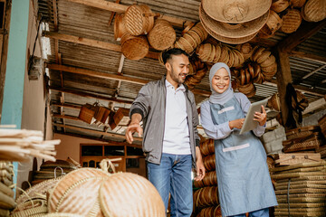 attractive muslim woman seller with customer in her traditional bamboo craft product workshop