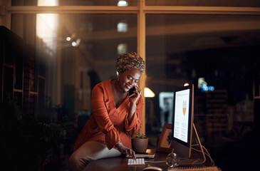 Ill save those details into the system now. a young businesswoman talking on a cellphone while using a computer in an office at night.