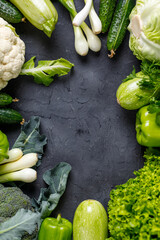 Frame of green raw vegetables on black background. Top view of healthy organic food. Copy space