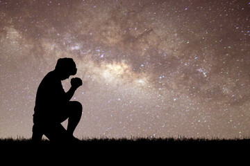 Man silhouette kneeling praying to god hopefully with the beautiful Milky Way
