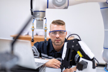Engineer sitting in robot fabrication room quality checking robot arm hardware engineering