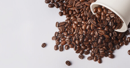 Fancy a cuppa. Studio shot of a tipped over paper cup filled with coffee beans against a white background.