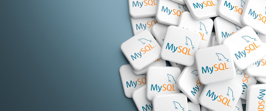 Logos of the open source database system MySQL on a heap on a table. Web banner format, copy space.