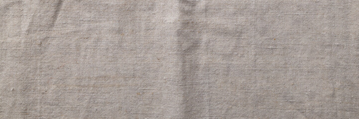 Natural linen fabric texture banner. Flaxen textile background, top view. Rough crumpled burlap panoramic web header. Wide screen wallpaper