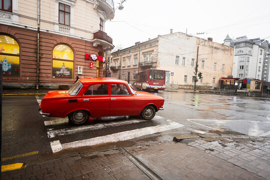 Ivano-Frankivsk, Ukraine - March, 2023: Red Moskvich AZLK Soviet classic retro car driving on rainy street.