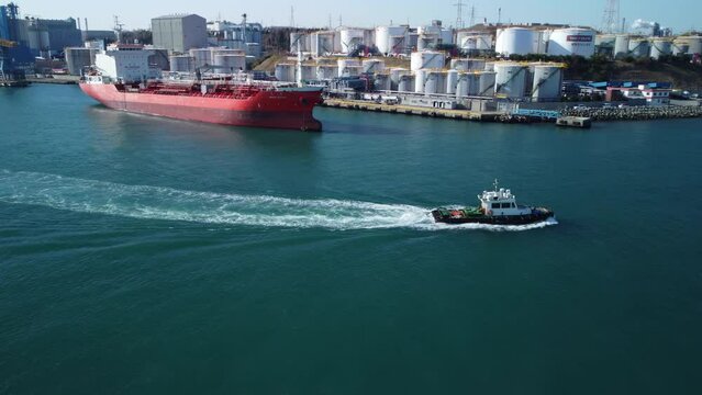Aerial horizontal view of a tug boat sailing in east sea in Nam-gu harbor, Ulsan industrial district, South Korea.