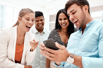 Take a look at this. a handsome young businessman showing his colleagues something funny on his cellphone.