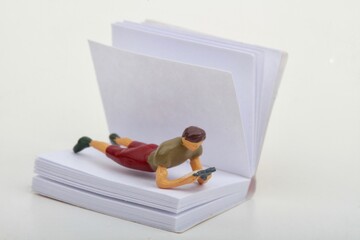 miniature figurine of a man reading inside a big paper book