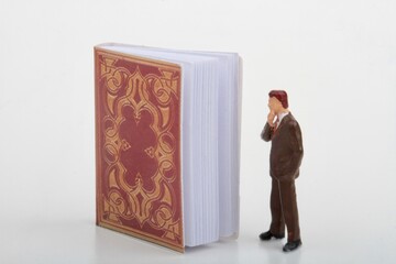 miniature figurine of a businessman looking at a big ancient book