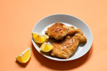 Classic fried Wiener Schnitzel served with lemon on a white plate. Breaded fried meat. A traditional dish of Austrian or German cuisine. Close-up. Copy space