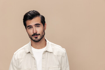 Portrait of a stylish male fashion model on a beige background in a white t-shirt looks at the camera, trendy clothing style, copy space, space for text