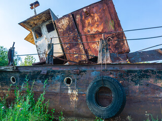 Old rusty ships lie on the riverbank. The river bank and rusting ships. Pier with old ships on the...