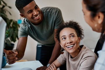 With teamwork anything is possible. a group of young businesspeople using a computer together in a modern office.