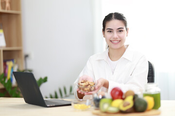 Beautiful smiling nutritionist looking at camera and showing healthy food in the consultation. - 583116457