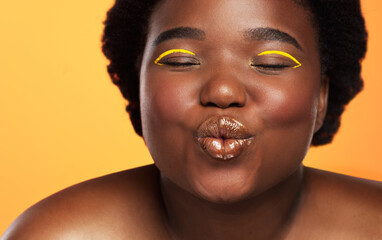 A playful heart is a pretty heart. Studio shot of a beautiful young woman posing against an orange background.
