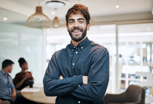 Im always on top of my game. Portrait of a young businessman standing in an office with his colleagues in the background.
