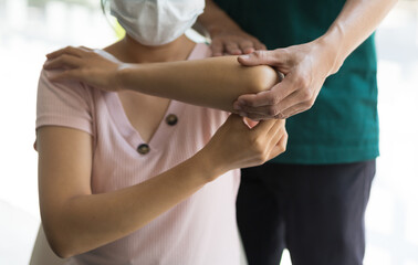 Obraz premium Woman with shoulder pain goes to the doctor. Concept of physical therapy and rehabilitation.