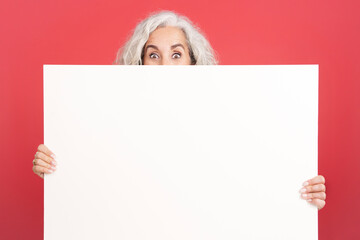 Mature woman hiding behind a blank panel