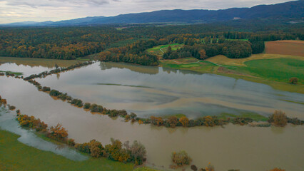 AERIAL: Picturesque countryside with a swollen muddy river overflowing its banks