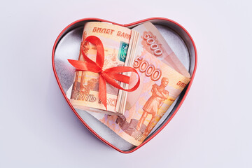 Russian rubles on white background, bundle of five thousand banknotes with red ribbon in heart box, money gift concept