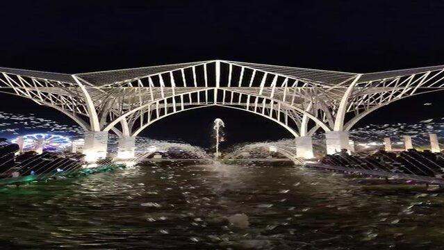 Slow motion footage of water droplets coming out of a fountain with a monument in background shot in City Park in Mansarovar at night