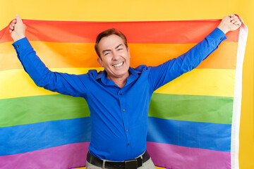 Happy mature man raising a lgbt rainbow flag