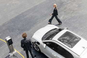 Aerial view progressive lifestyle of businesspeople with electric car connected to charging station...