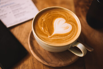 Top view of aroma cappuccino coffee art with heart of milky foam standing on wooden table for...