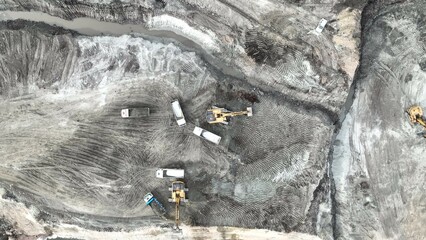 Excavator Working On Huge Mining Site, Loading The Trucks, Trucks Transport The Material, aerial view.