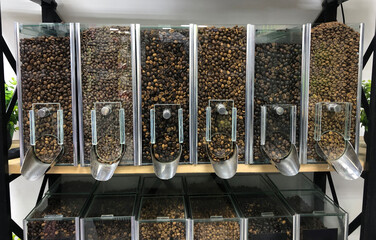 Different types of coffee beans in containers dispensers for self-service in supermarket