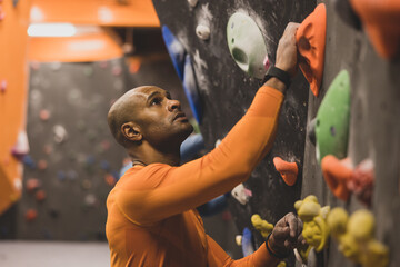 Male Rock Climber looking up at a climbing wall planning route