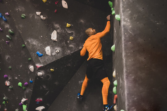 African American Male Rock Climber Climbing Up Bouldering Wall