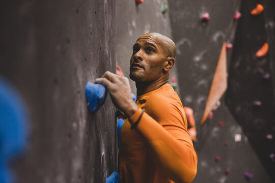Close up male rock climber looking up with focus at a climbing wall planning route