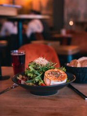 Bunter Salatteller mit angebratenem Ziegenkäse, Kräutern und Granatapfelstücken in einem gemütlichen Restaurant - Perfekt für gesunde Ernährung oder Restaurant-Marketing.