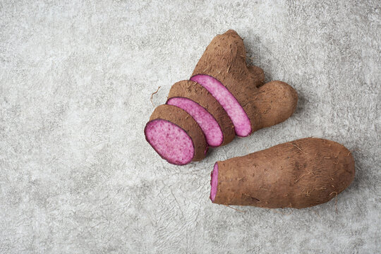 sliced purple yam on a white textured surface, dioscorea alata, aka ube, violet yam, water or greater yam, purple-fleshed tubers used in cuisine and traditional medicine, copy space