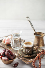 Obraz na płótnie Canvas Cup of coffee and glass of water and dry dates on saucer ready to eat for iftar time. Islamic religion and ramadan concept.
