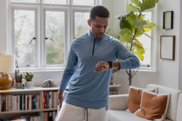African American male getting ready to leave for a run checking his smartwatch