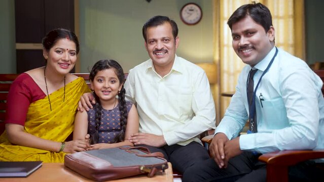 Focus on family, Happy smiling banker looking camera in front of middle class family with kid at home - concept of doorstep banking, financial adviser and professional occupation.