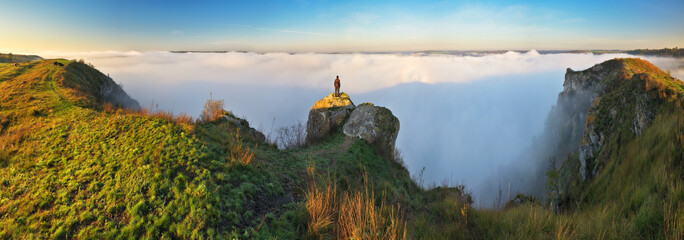 woman stands on a rock above a river canyon. female tourist enjoys foggy autumn landscape. nature of Ukraine