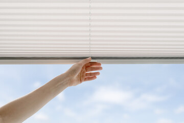 woman open cordless blind shutter on window - obrazy, fototapety, plakaty