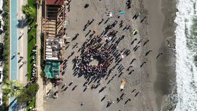 Aerial view of a priest and a group of people on the beach performing a baptism ritual