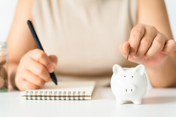 Obraz na płótnie Canvas Closeup of woman hand putting money coin into piggy bank for saving money. saving money and financial concept