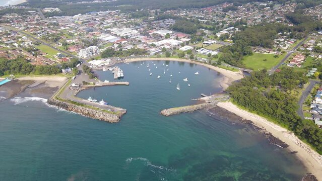 Aerial drone pullback reverse view of Ulladulla in the City of Shoalhaven, NSW, Australia, showing Ulladulla Harbour 