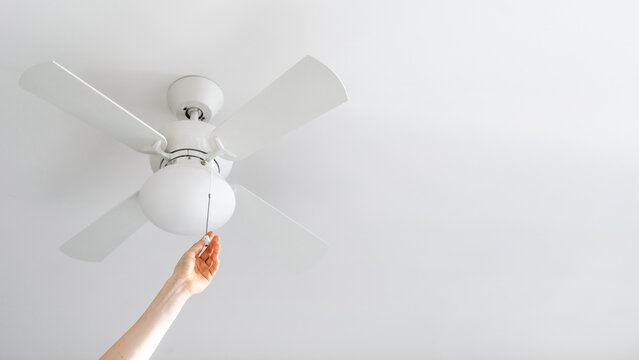 Person Turn On Electric Ceiling Lamp With Propeller Indoors