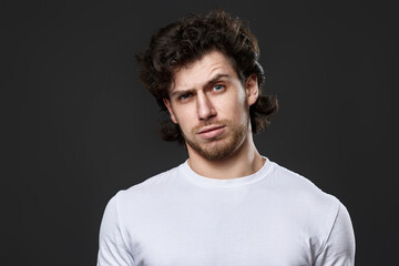 skeptic and nervous man in white t-shirt on dark gray background