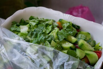 High-angle view of a simple salad with cucumber, tomatoes, and lettuce on a paper plate