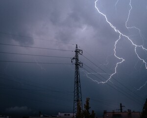 Lightning striking above a transmission tower on a dark gloomy and cloudy evening