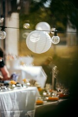 Vertical shot of hanging lightbulbs and lanterns near cafe tables