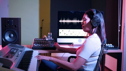 Beautiful stylish young woman sound producer sitting at the controls in the recording studio