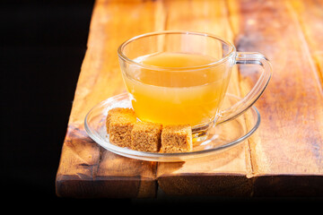 Cane panela tea in a glass cup, on a wooden surface, royalty free